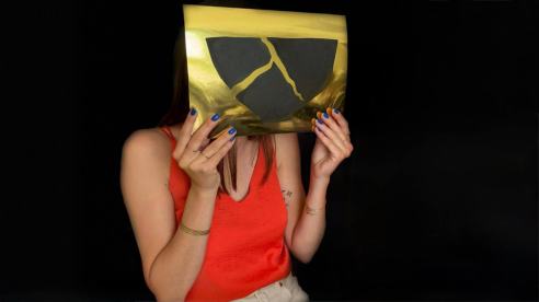 femme tenant devant elle une oeuvre noir et or en collage qui représente un kintsugi stylisé